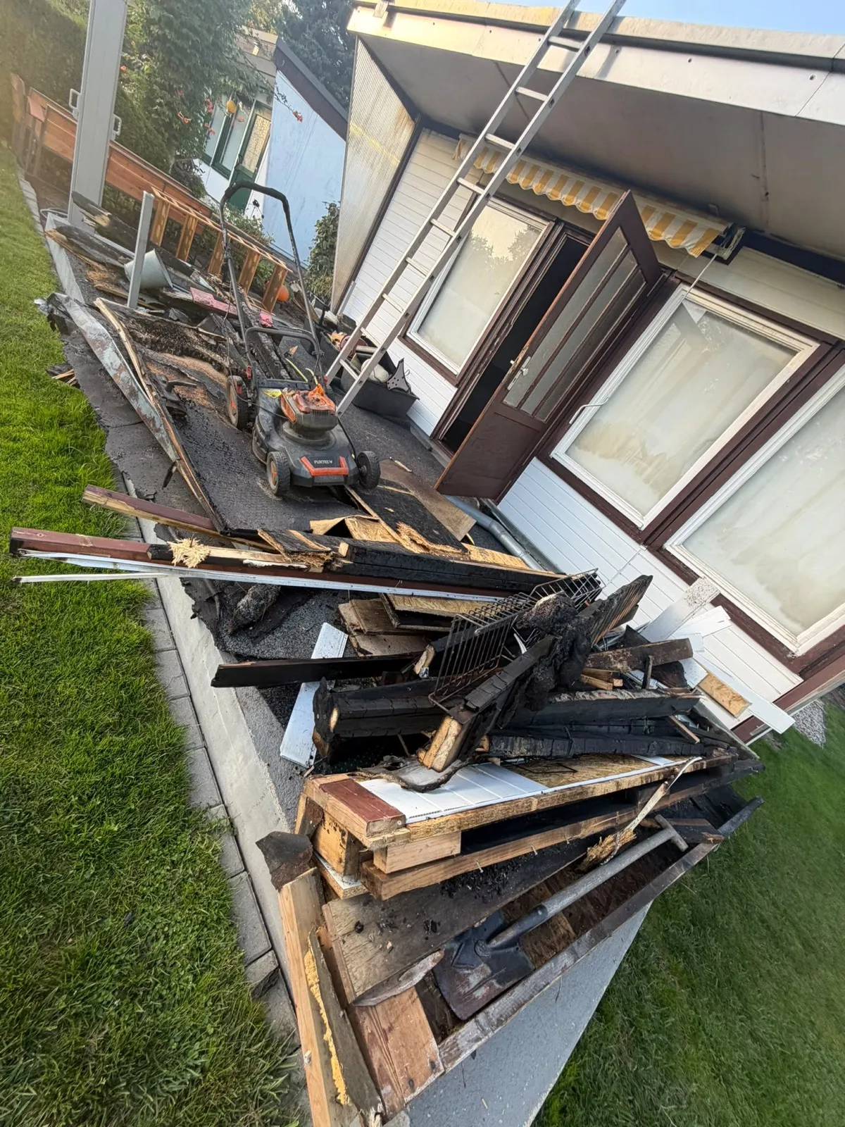 Verkohlte Balken und Bretter vor einem brandgeschädigten Gartenhaus in Berlin-Rahnsdorf