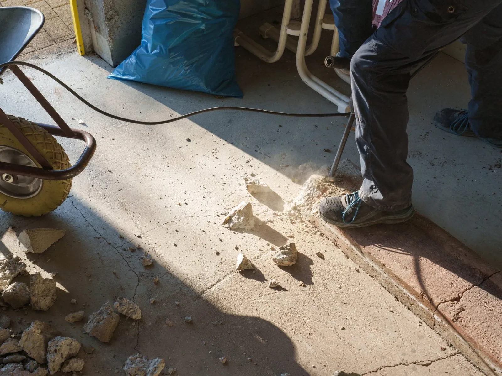 Arbeiter bricht mit dem Abbruchhammer einen Betonboden auf