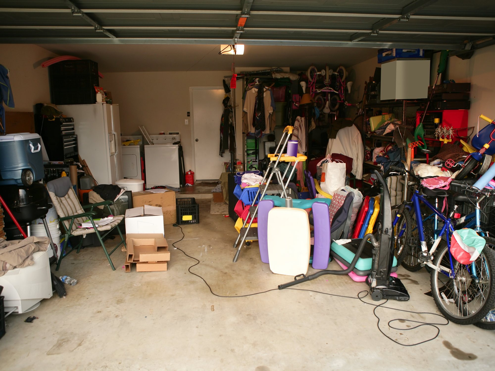 Vollgestellte Garage mit Fahrrädern, Geräten und Metallteilen vor der Räumung