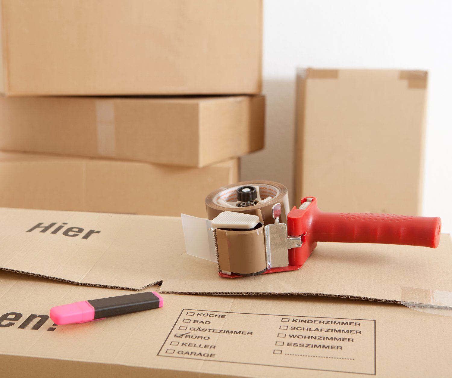Beschriftete Umzugskartons mit Packliste und Klebebandroller