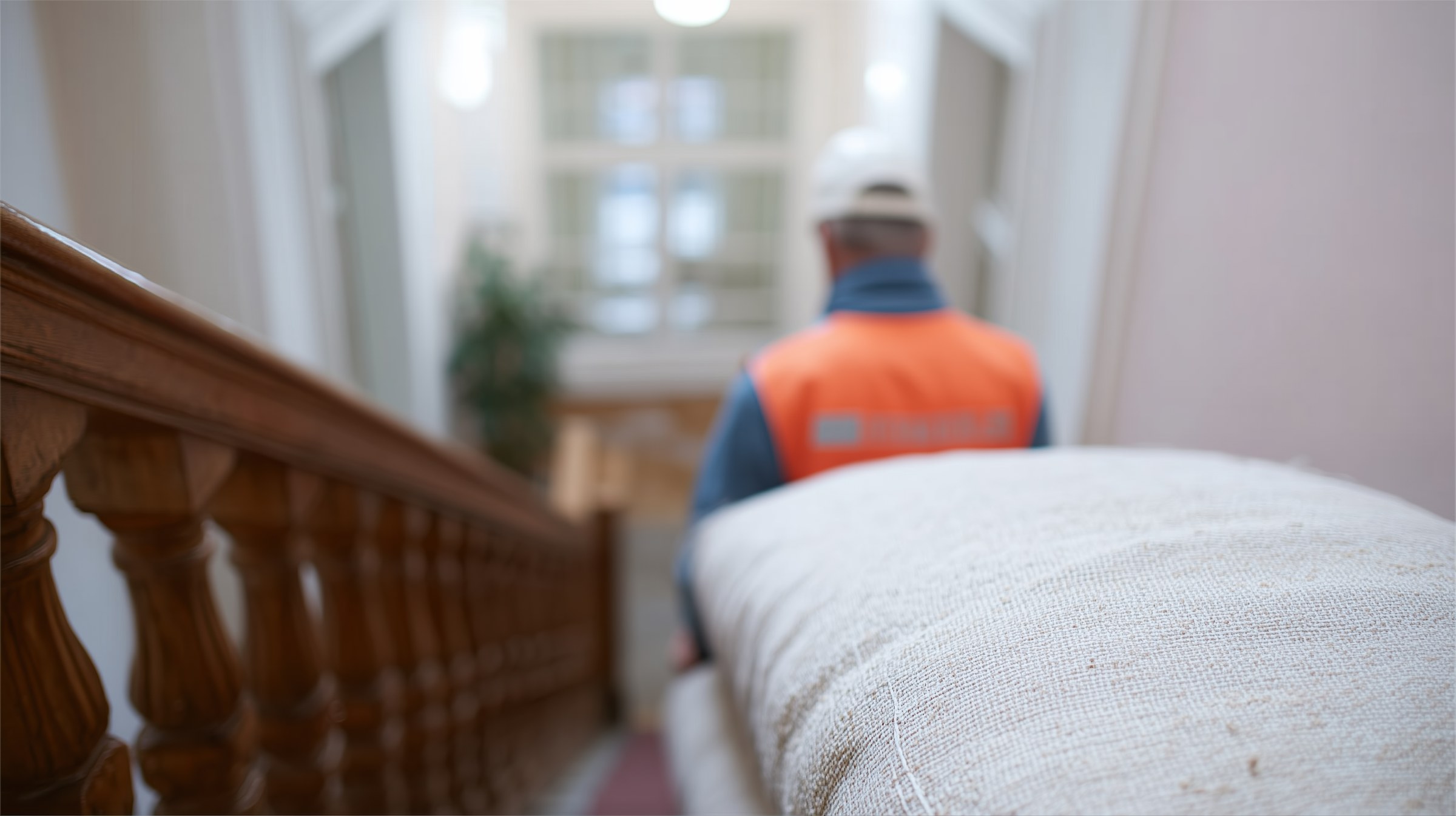 Mitarbeiter trägt ein Sofa ein Altbautreppenhaus hinunter