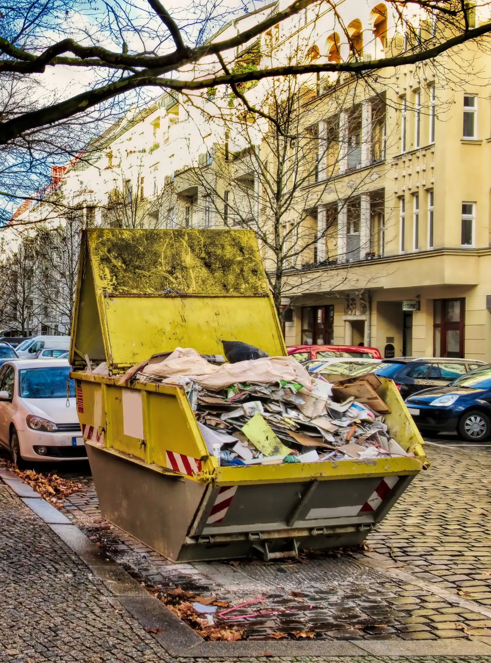 Gefüllter Absetzcontainer am Straßenrand einer Berliner Altbaustraße