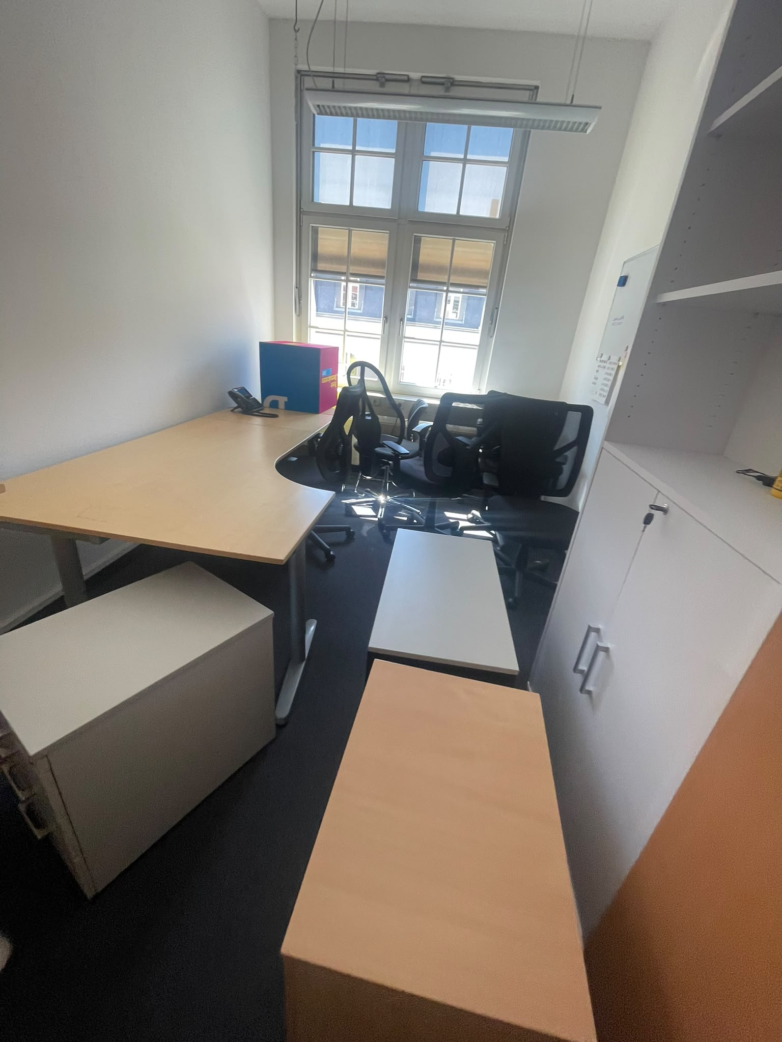 Büroraum mit Schreibtischen, Bürostühlen und Schränken vor der Abholung