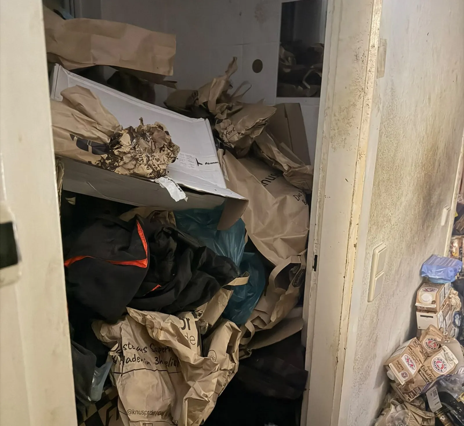 Mit Müllsäcken und Papiertüten zugestellter Flur vor der Reinigung