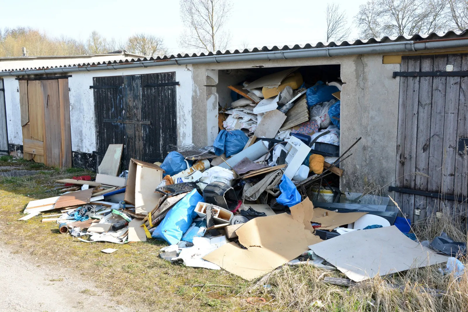 Ausgeräumte Garage mit Sperrmüll und Bauschutt davor