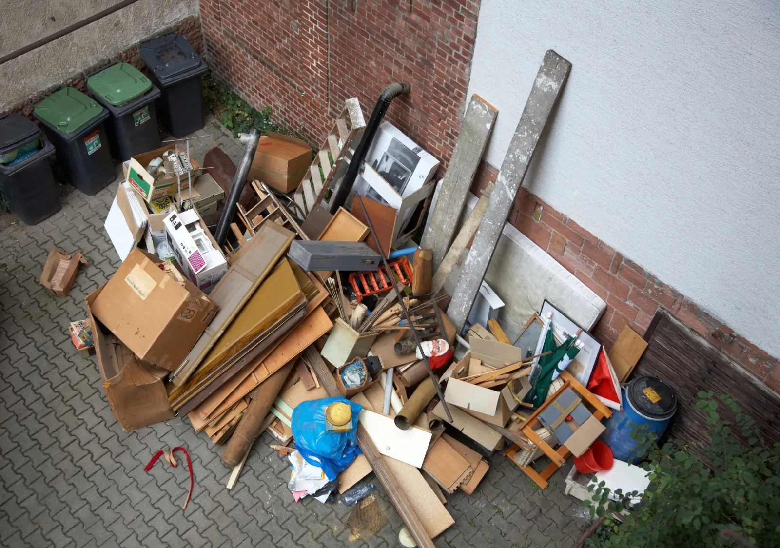 Sperrmüllhaufen im Hinterhof neben Mülltonnen
